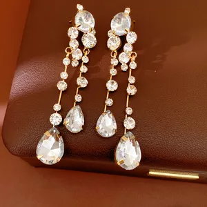 Detailed view of elegant gold-tone earrings with teardrop and round rhinestones