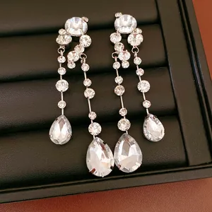 Detailed shot of silver needle earrings featuring round and teardrop-shaped crystals