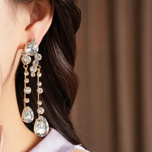 Elegant silver needle earrings with teardrop crystals worn by a model for a close-up