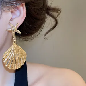 Detailansicht der eleganten goldenen Seestern und Muschel Ohrhänger an einem Modell
