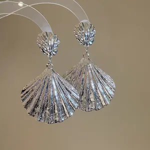 Detailansicht der silbernen Metall-Ohrhänger in Muschelform mit feiner Texturierung.