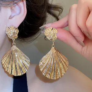 Nahaufnahme der filigranen Metallstruktur dieser goldenen Ohrringe in Muschelform.