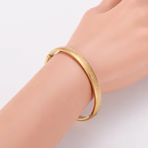 Detail view of 18k gold plated stainless steel bangle with spotted texture on a hand model.