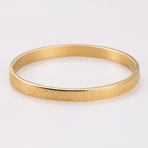 Detail view of a gold-plated stainless steel bangle with unique spotted texture patterns.