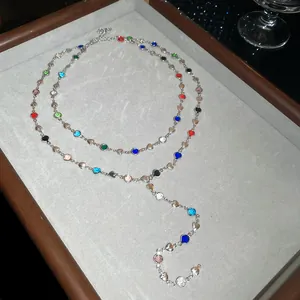 Gros plan d'un collier en Y avec cristaux multicolores et breloques en forme de cœur.