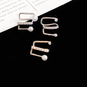 Close-up of three fashion pearl and zircon ear cuffs on black background