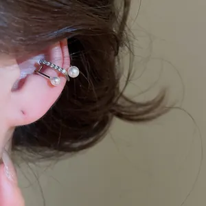 Close-up of a silver-toned double-layer ear cuff with pearls and zircons worn on the ear.
