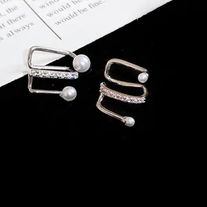 Close-up of elegant silver-toned ear cuffs with pearls and zircon details on black background