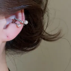 Detail view of a silver double-layer ear cuff with zircons and pearls on an ear.