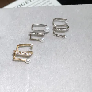 Close-up detail of elegant zircon and pearl ear cuffs for non-pierced ears in silver and gold