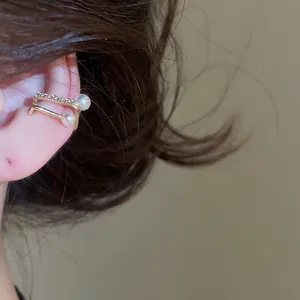 Detailed macro shot of a double-layer gold ear cuff featuring zircon stones and pearls