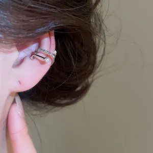 Close-up view of a minimalist silver ear cuff with pearls and crystals worn on the ear bone