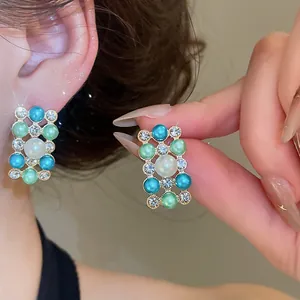 Close-up detail of French vintage style pearl and rhinestone stud earrings on model's ear