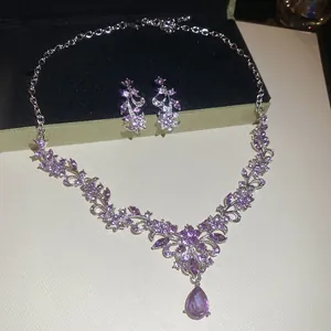 Detailed view of sparkling jewelry set featuring purple crystals and teardrop pendant