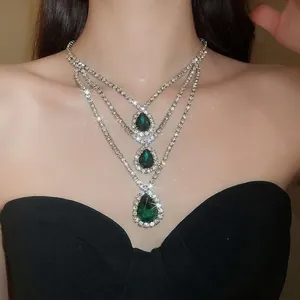 Close-up of a three-tier necklace with sparkling green teardrop pendants and rhinestones