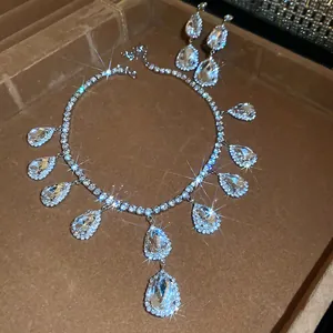 Close-up of sparkling teardrop pendant necklace and matching earring set with starburst shine.