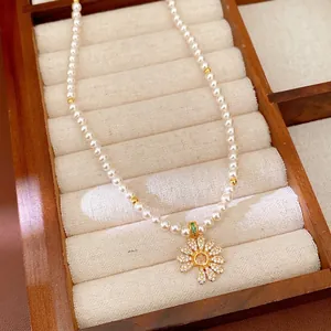 Halskette aus Perlen mit 18 Karat Vergoldung und Zirkonia-Blumenanhänger auf Tablett
