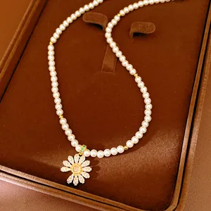 Detail einer Perlenkette mit einem exquisiten, mit Zirkonia besetzten Gänseblümchen-Anhänger.