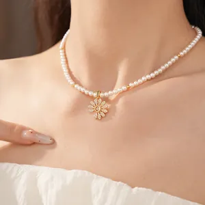 Elegante Nahaufnahme einer 18k vergoldeten Perlenkette mit Zirkonia-Blumenanhänger am Schlüsselbein