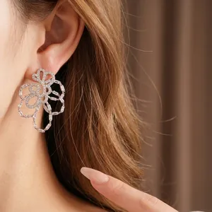 Elegant 18k gold-plated zircon hollow flower stud earrings shown on model's ear