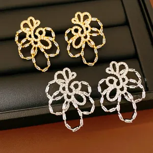 Detailed view of hollow flower earrings with sparkling zircon inlay in gold and silver