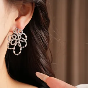 Detailed close-up view of elegant silver-toned hollow flower earrings with sparkling zircons