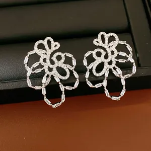 Detailed view of 18k gold plated silver needle hollow flower stud earrings with zircons
