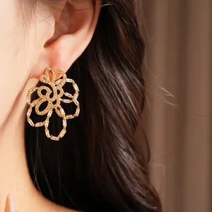Close-up detail of 18k gold-plated hollow flower stud earrings with shining zircons