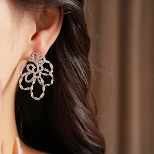 Close-up of 18k gold plated hollow flower stud earrings with sparkling zircon on ear