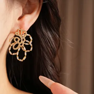 Close-up of 18k gold plated hollow flower stud earrings with sparkling zircon stones.