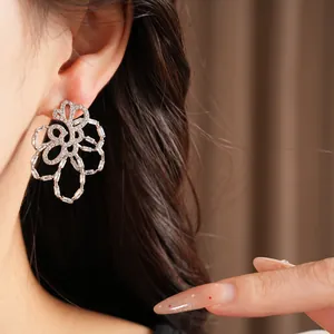Detailed close-up of a sparkling 18k gold plated hollow flower earring with zircons