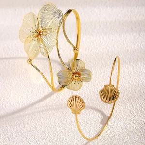 Dettaglio di bracciali da braccio dorati con fiori in filigrana e motivi a conchiglia