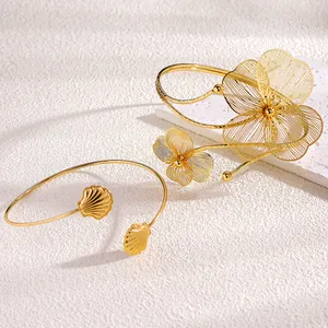Vista dettagliata di bracciali regolabili dorati con fiori in filigrana e conchiglie
