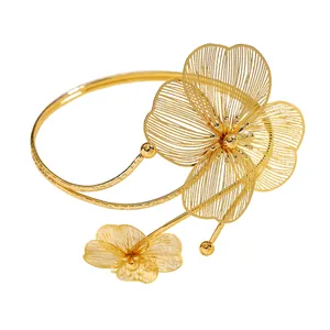 Dettaglio ravvicinato di un bracciale da braccio in oro con fiori traforati e regolabile.