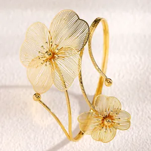 Dettaglio del bracciale da braccio dorato regolabile con fiori traforati.
