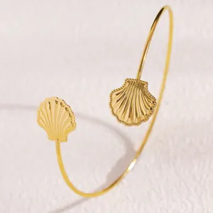 Dettaglio di un raffinato bracciale da braccio regolabile dorato a forma di conchiglia.
