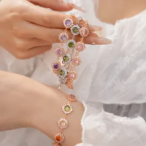 Dettaglio di eleganti bracciali in oro rosa con gemme colorate e motivo halo in zirconi