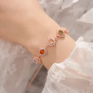 Dettaglio di un bracciale in oro rosa con zirconi tondi colorati su pizzo bianco