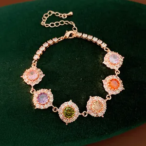 Primo piano di un bracciale in oro rosa con zirconi multicolori su velluto verde.