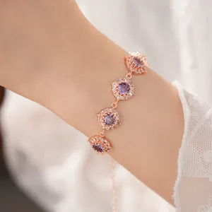 Primo piano di un bracciale in oro rosa con ciondoli rotondi in zirconia viola al polso