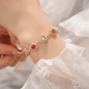 Dettaglio di un bracciale placcato oro rosa con zirconi colorati su un polso.