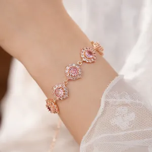 Primo piano di un bracciale in oro rosa con ciondoli floreali e zirconi cubici rosa