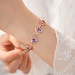 Vista ravvicinata di un bracciale in oro rosa con pietre di zircone viola scintillanti al polso.