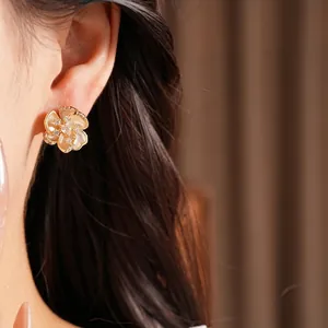 Elegantes pendientes de flor bañados en oro con circonitas brillantes en una modelo asiática
