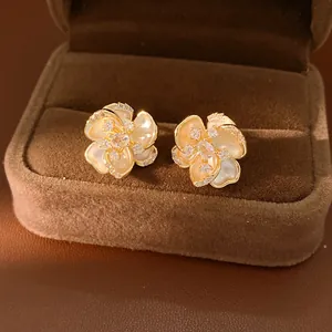Detalle de pendientes de flor chapados en oro con pétalos nacarados brillantes