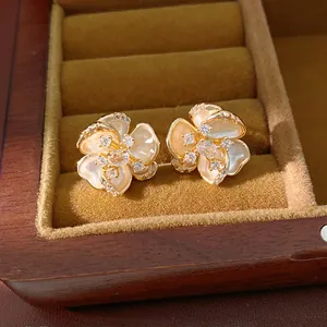 Primer plano de pendientes de flor dorada con circonitas brillantes en un joyero elegante.