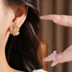 Primer plano detallado de pendientes de flores bañados en oro con circonitas en la oreja