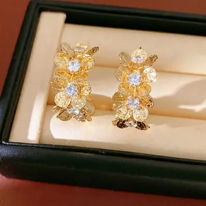 Elegant gold C-shaped hoop earrings with textured flower design and zirconia stones