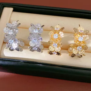 Detailed macro view of gold and silver zircon flower earrings in a velvet jewelry box.