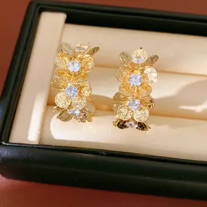 Detailed close-up of gold flower C-shaped stud earrings inlaid with sparkling cubic zirconia.